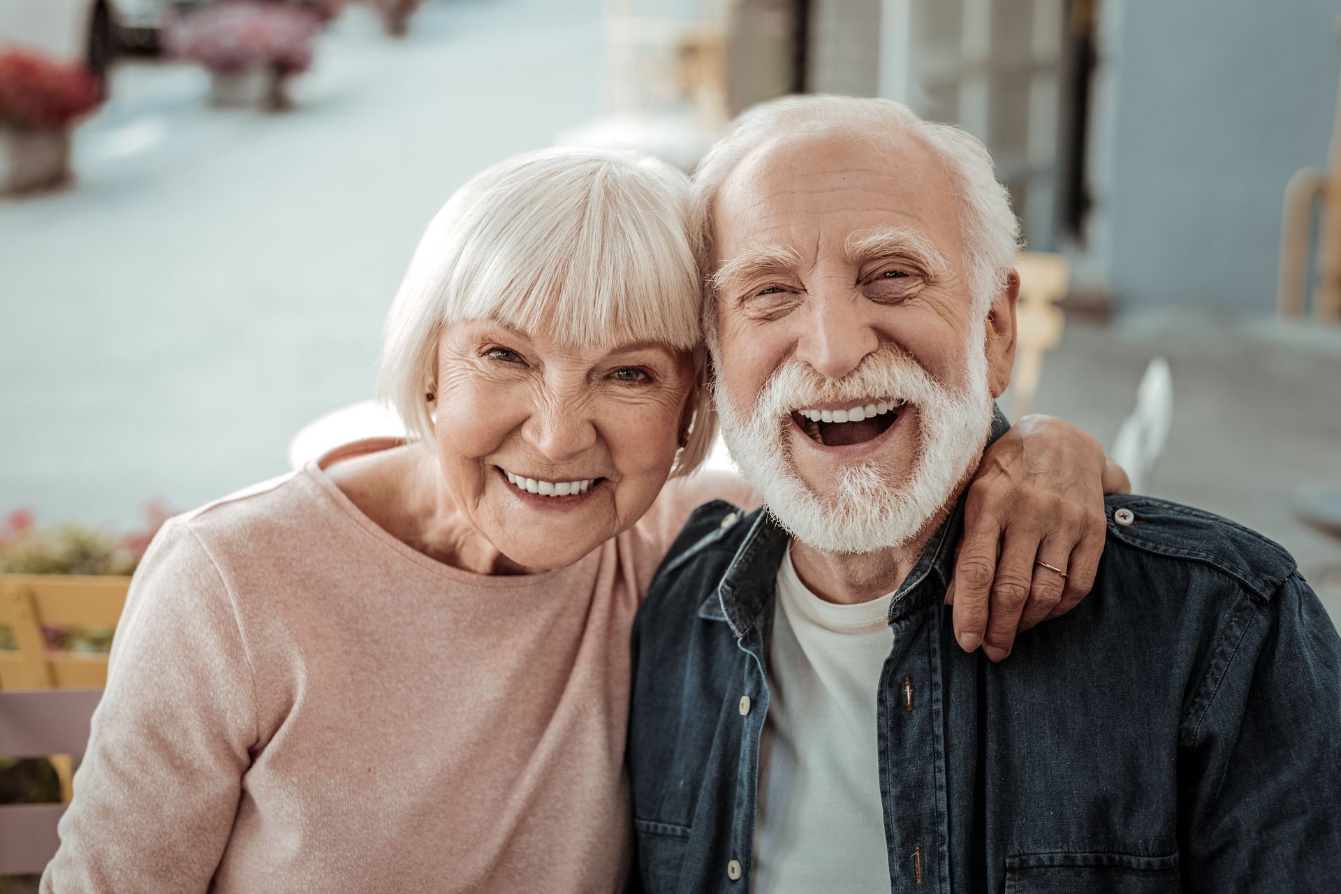 An elderly man and a woman are posing for a picture and smiling for the camera.