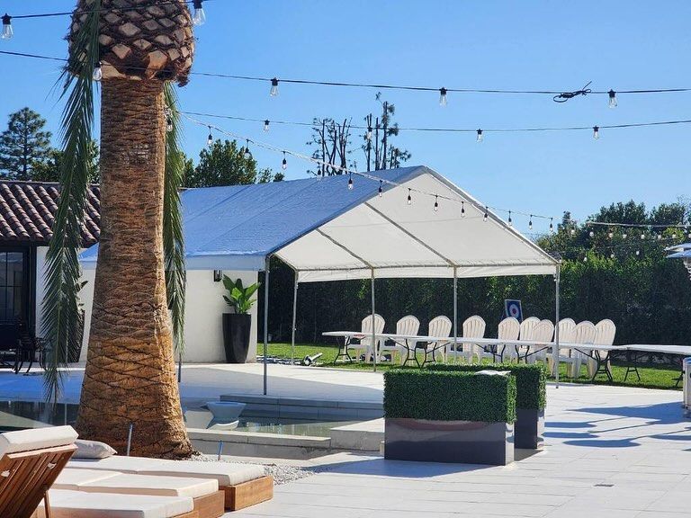 A large white tent is sitting next to a palm tree.