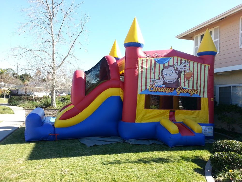A curious george bouncy house is in front of a house