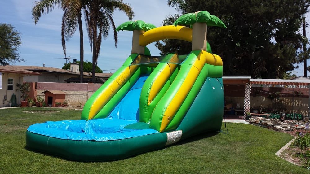 A green and yellow inflatable water slide in a backyard