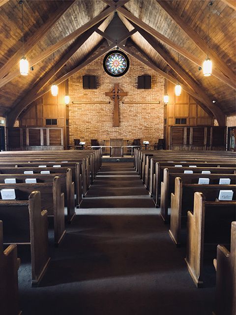 a church with rows of wooden benches and a cross on the wall