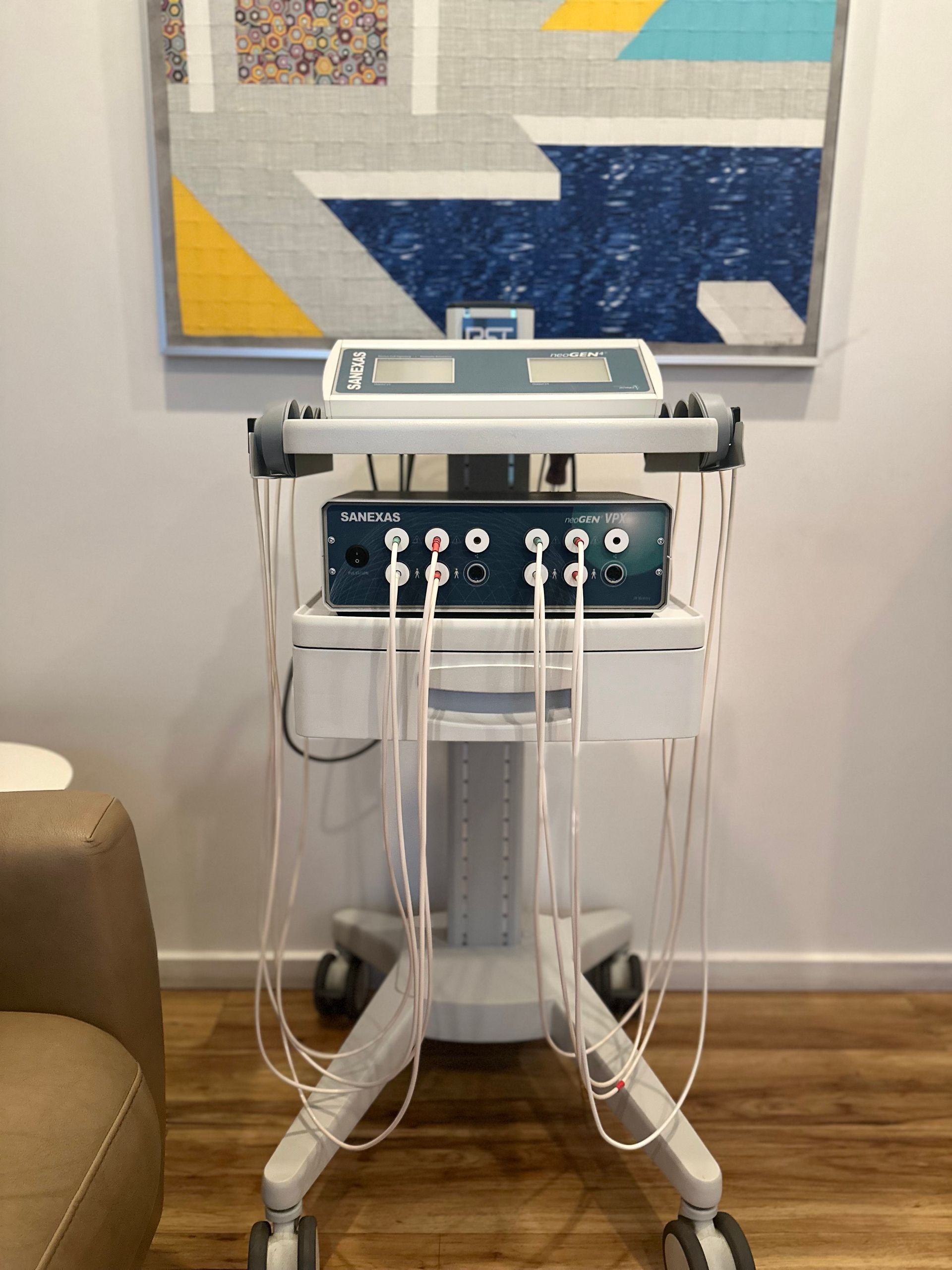 A medical device is sitting on a cart in front of a painting.