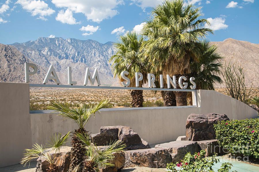There are palm trees in the foreground and mountains in the background.