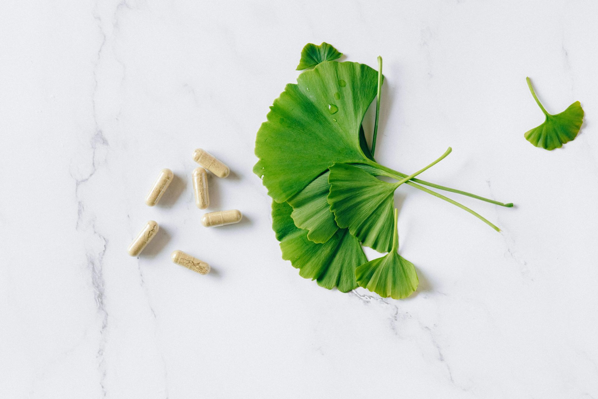 A wooden spoon filled with green powder , pills , and a magnifying glass.