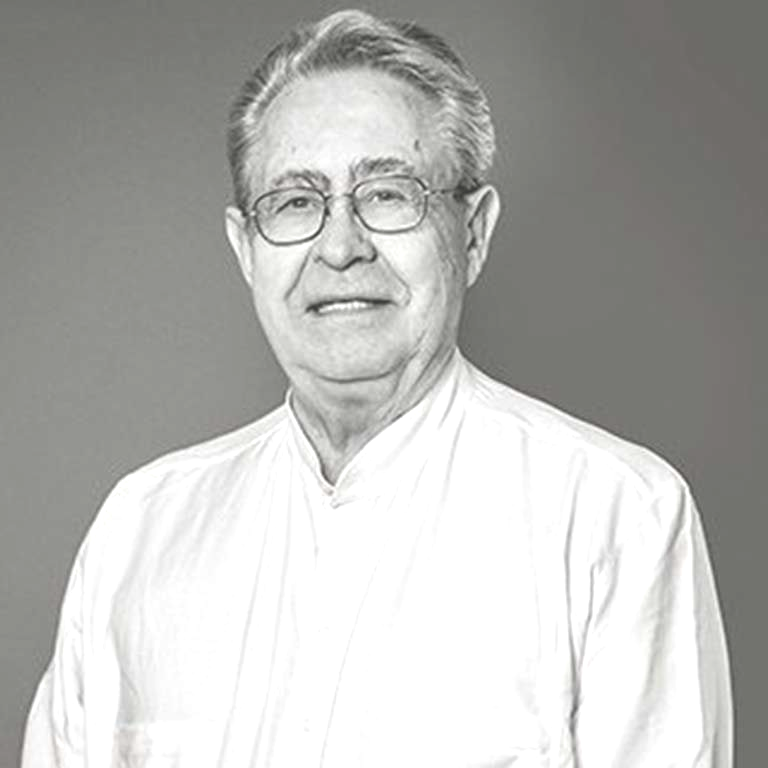 Mann mit Brille und hellem Hemd, lächelt und blickt in die Kamera. Schwarz-Weiß-Aufnahme, Studioaufnahme.