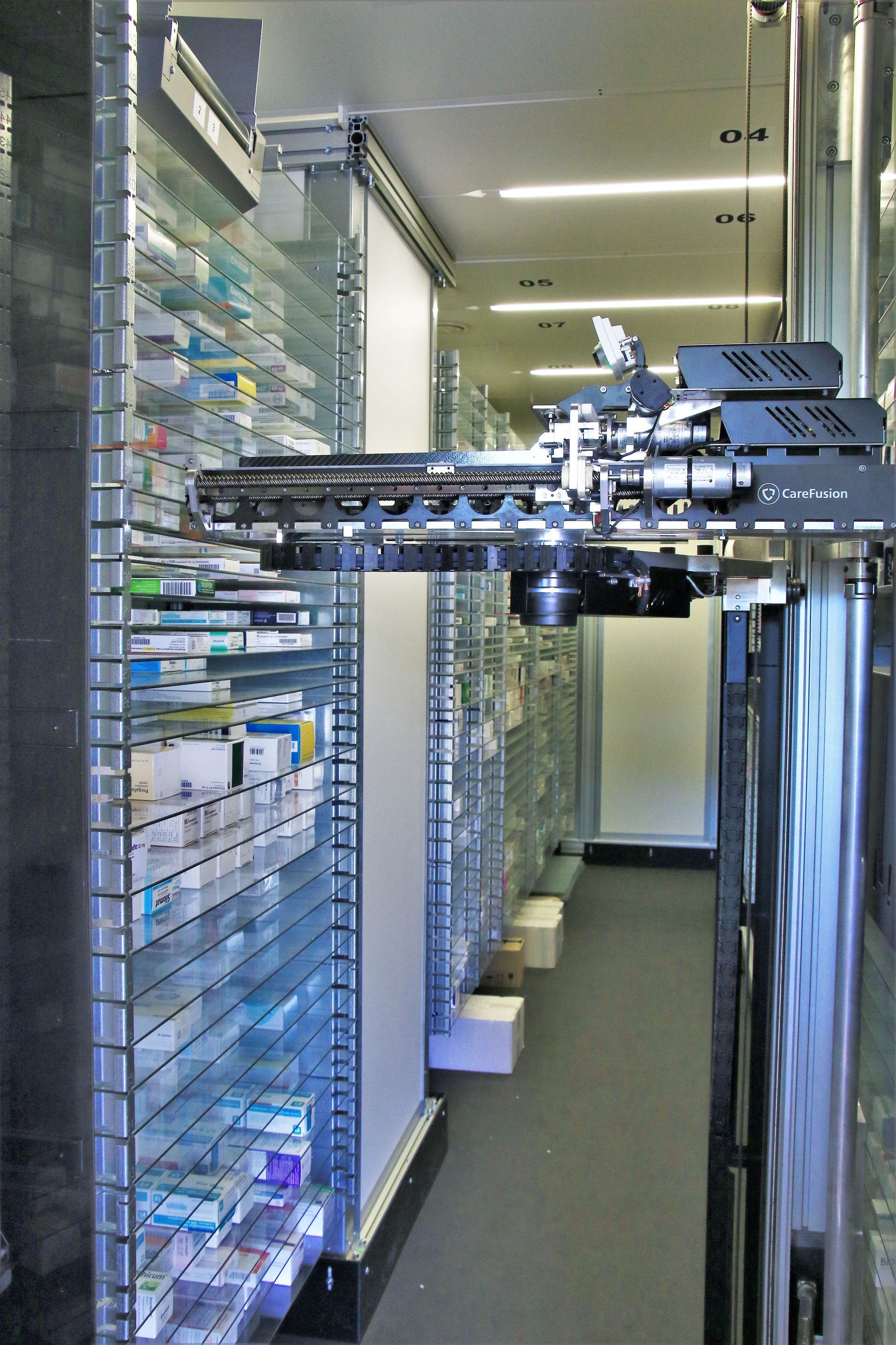 Automatisiertes Apothekensystem: Roboterarm entnimmt Medikamente aus Regalen.