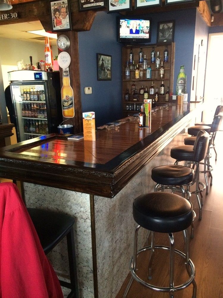 A long bar with stools and a sign that says beer 30