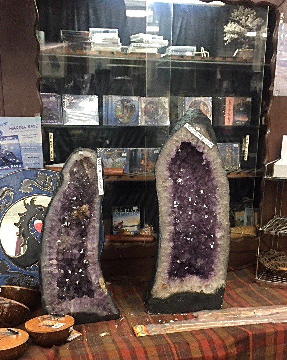 Two large purple crystals are sitting in front of a glass display case.