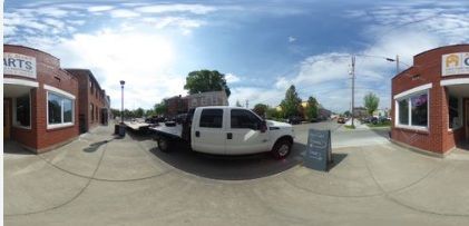 A 360 degree view of a building with cars parked in front of it