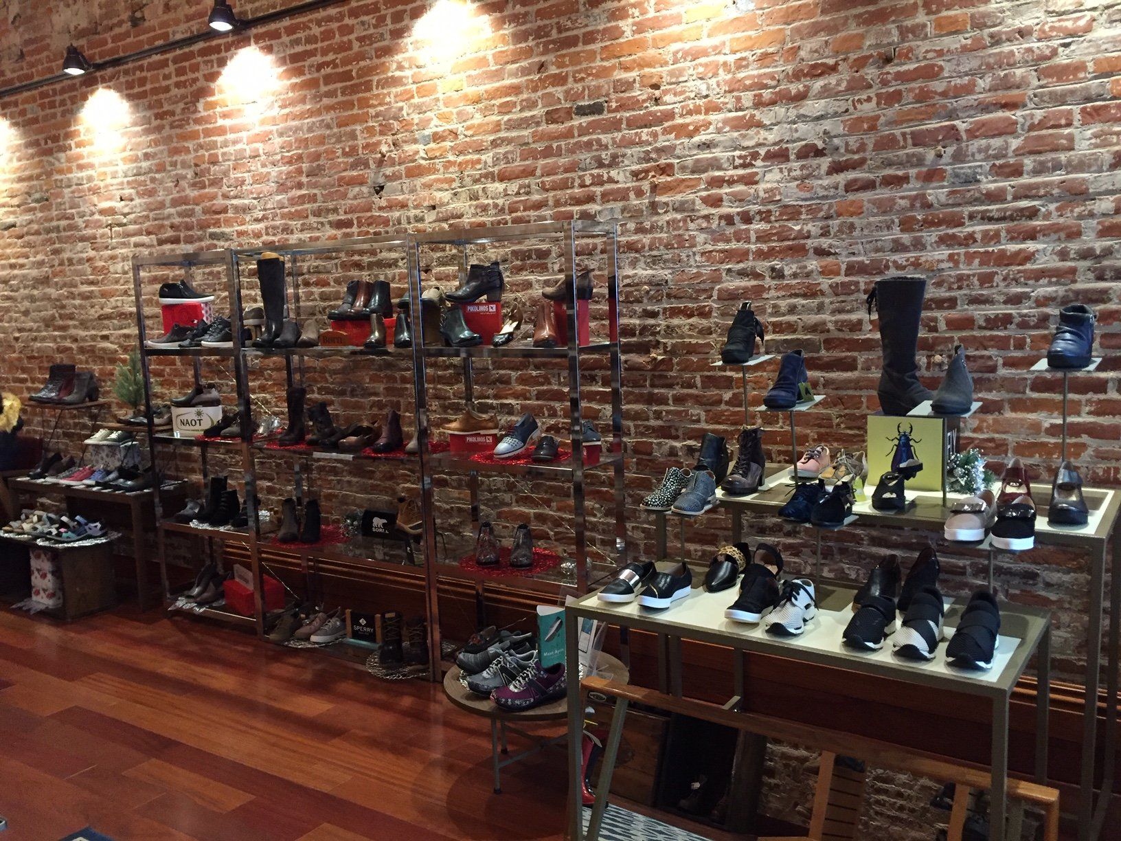 A store filled with lots of shoes and a brick wall.