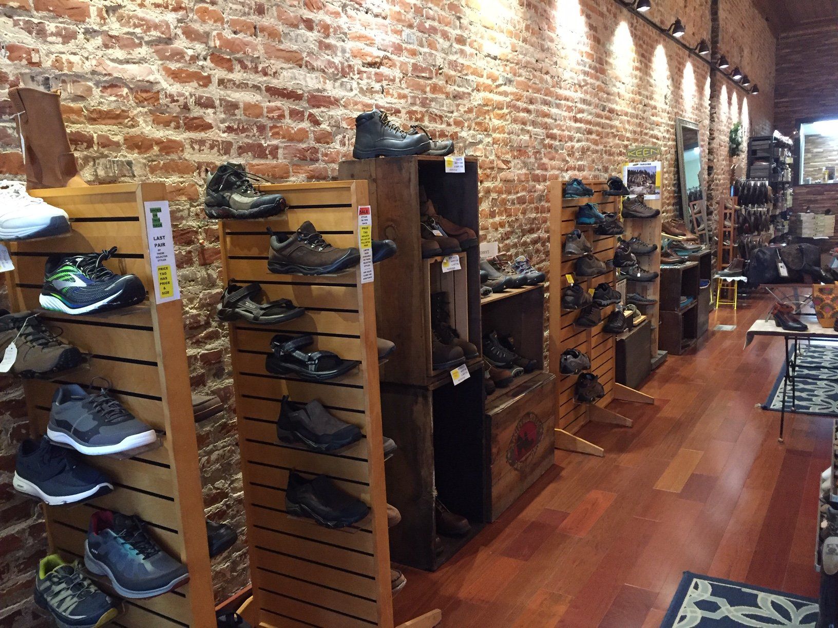 A store filled with lots of shoes and a brick wall.
