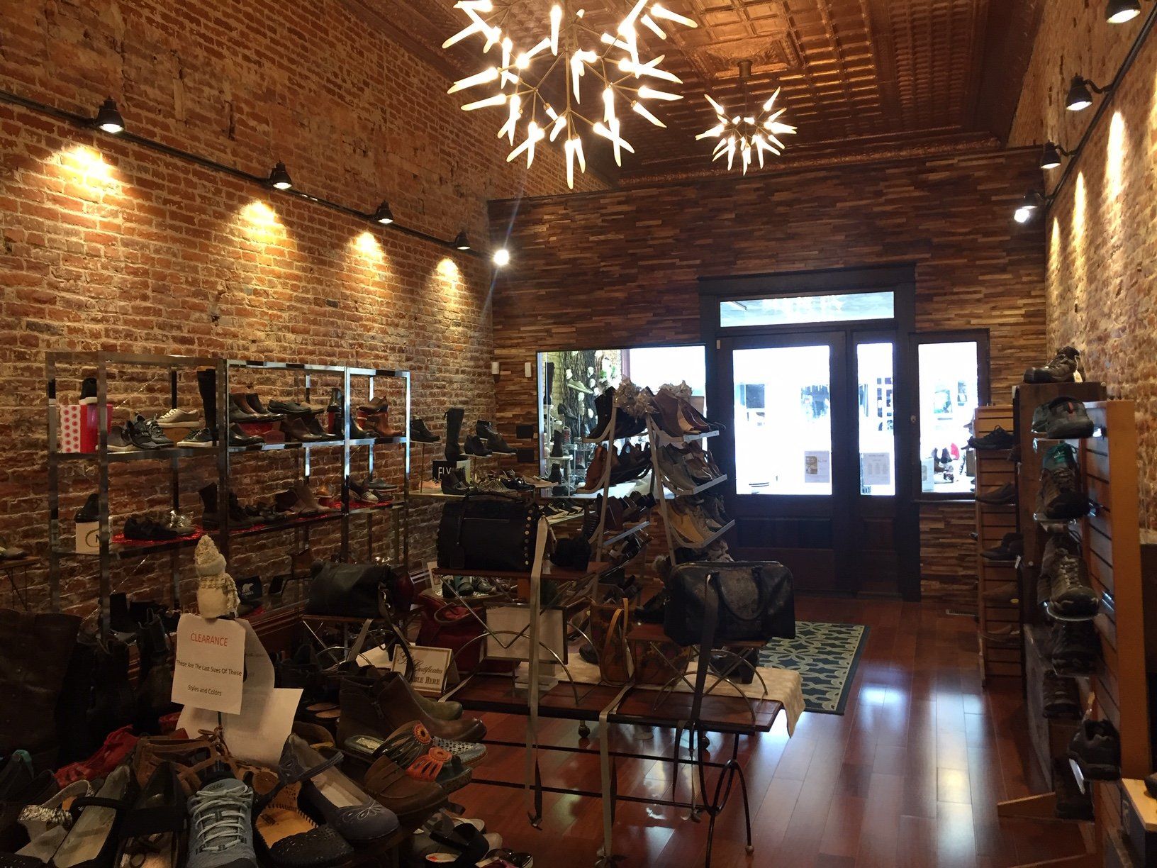A shoe store with a brick wall and a chandelier hanging from the ceiling.