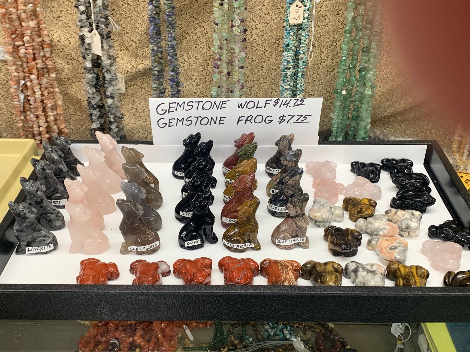 A display case filled with various types of rocks and a sign that says ' gemstone wolf ' on it.