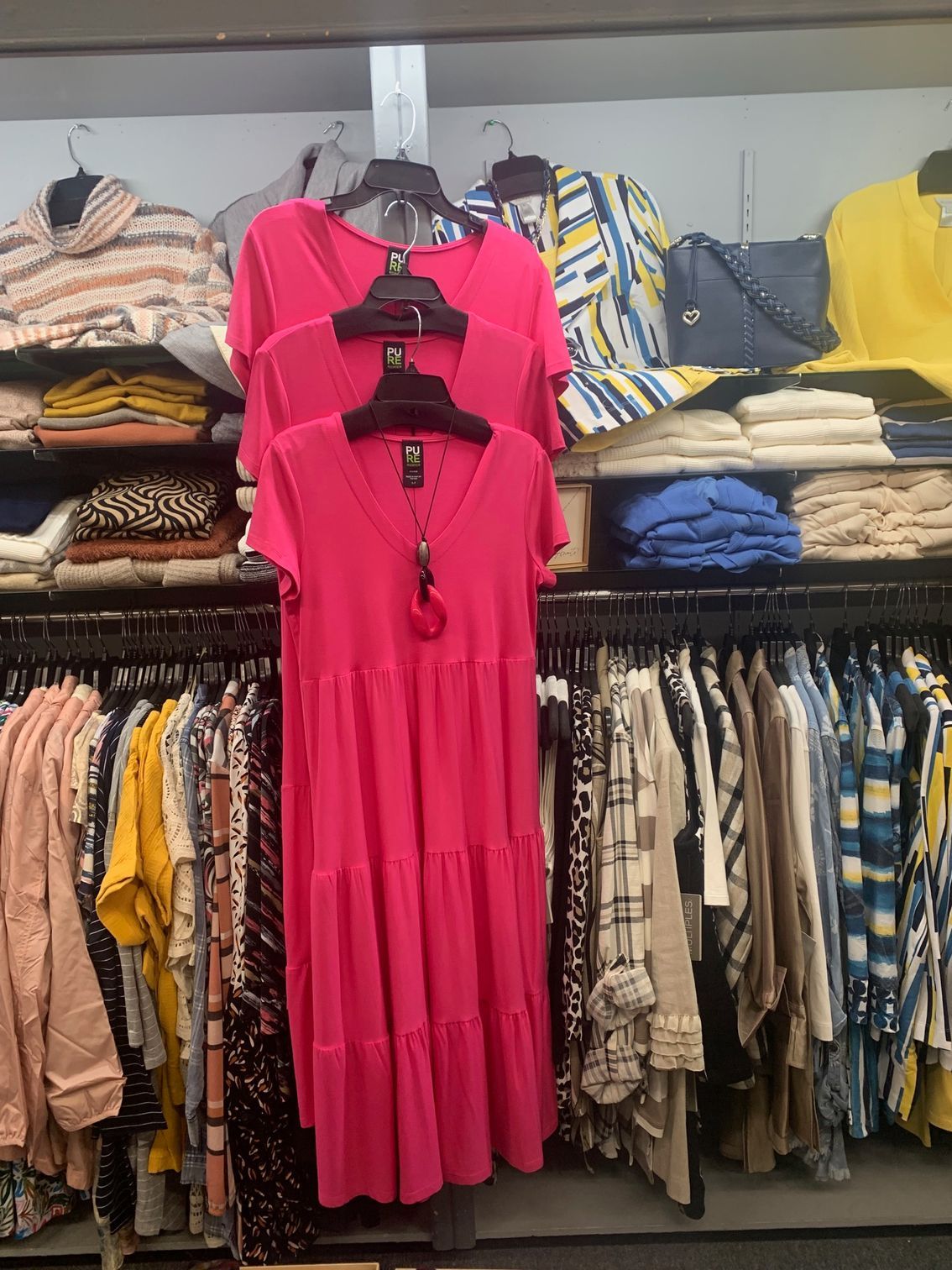 A pink dress is hanging on a rack in a clothing store.