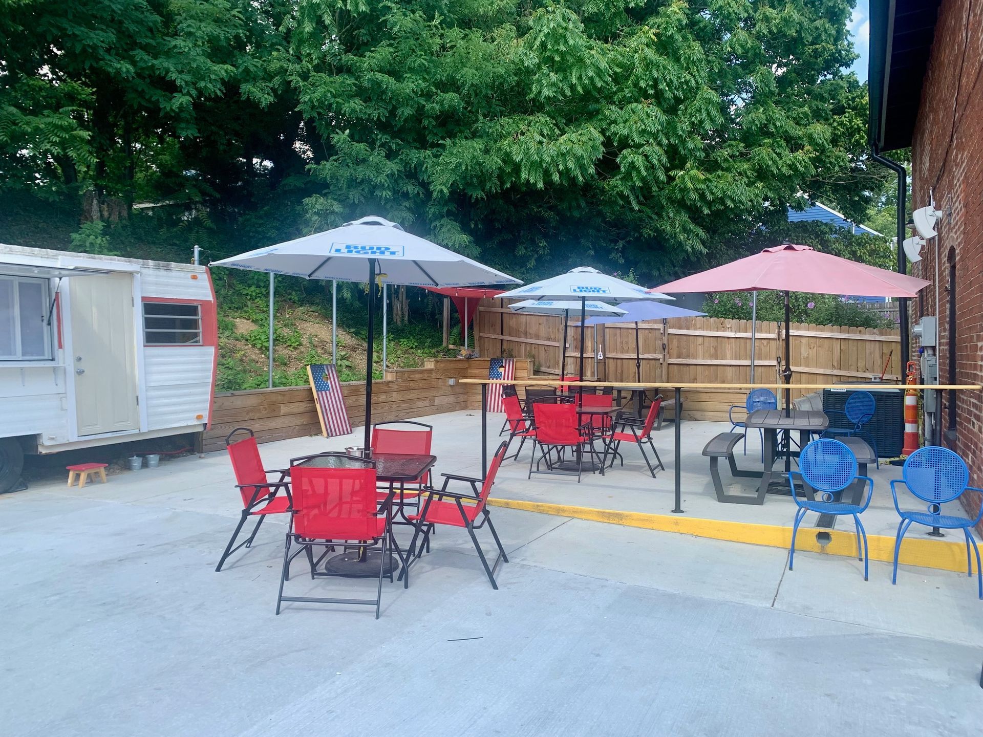 A patio with tables and chairs and umbrellas in back of a building.