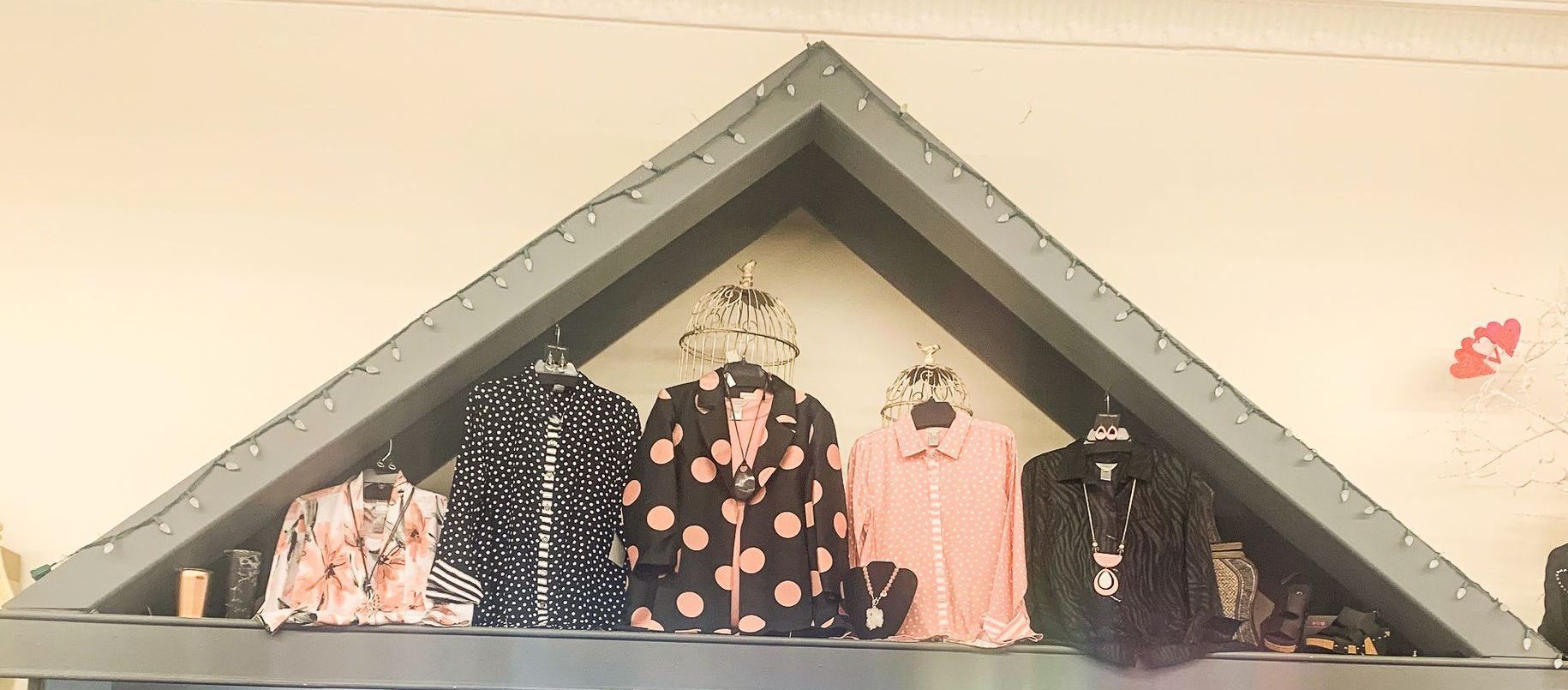 A display of clothes in a store with a triangle shaped shelf.