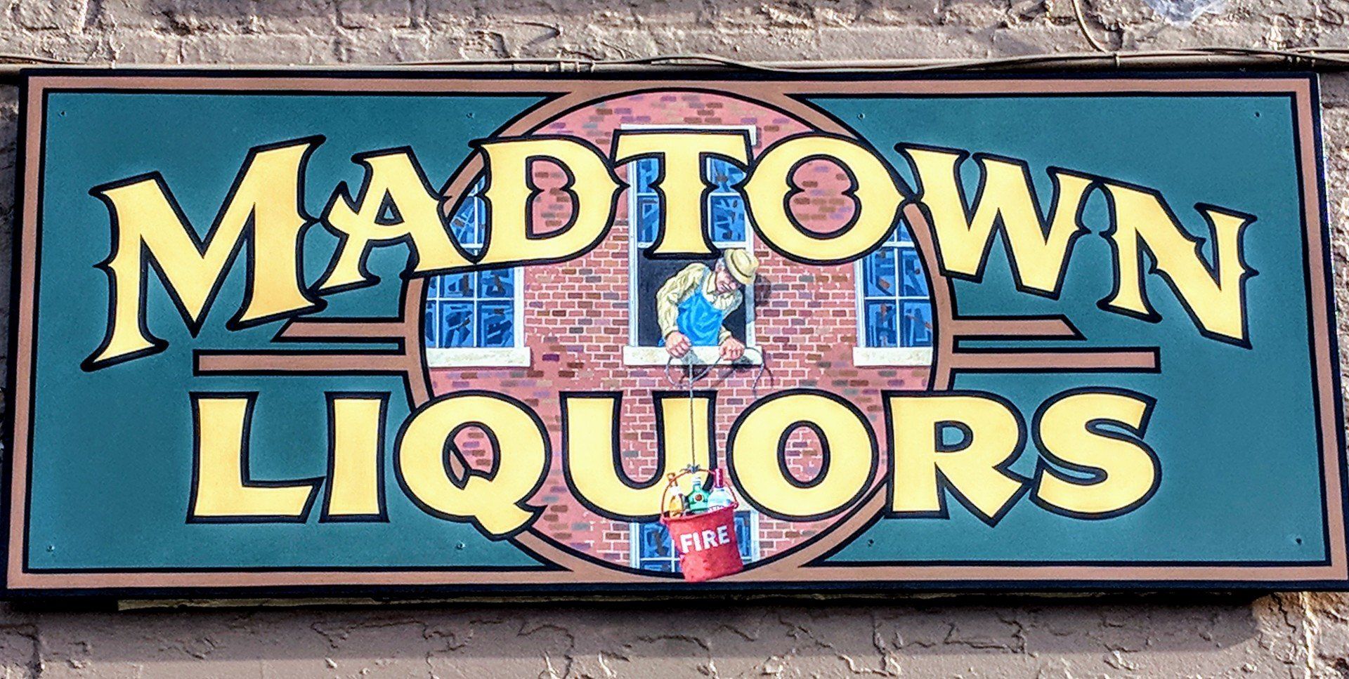 A sign for madtown liquors hangs on a brick wall