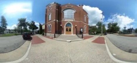 A 360 degree view of a brick building with a car parked in front of it.