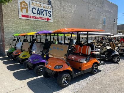 A row of golf carts are parked in front of a building.