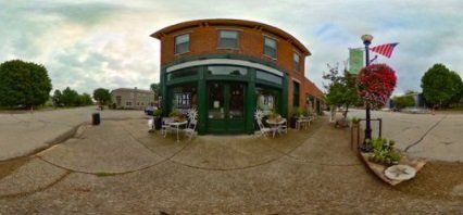 A 360 degree view of a building with tables and chairs in front of it.