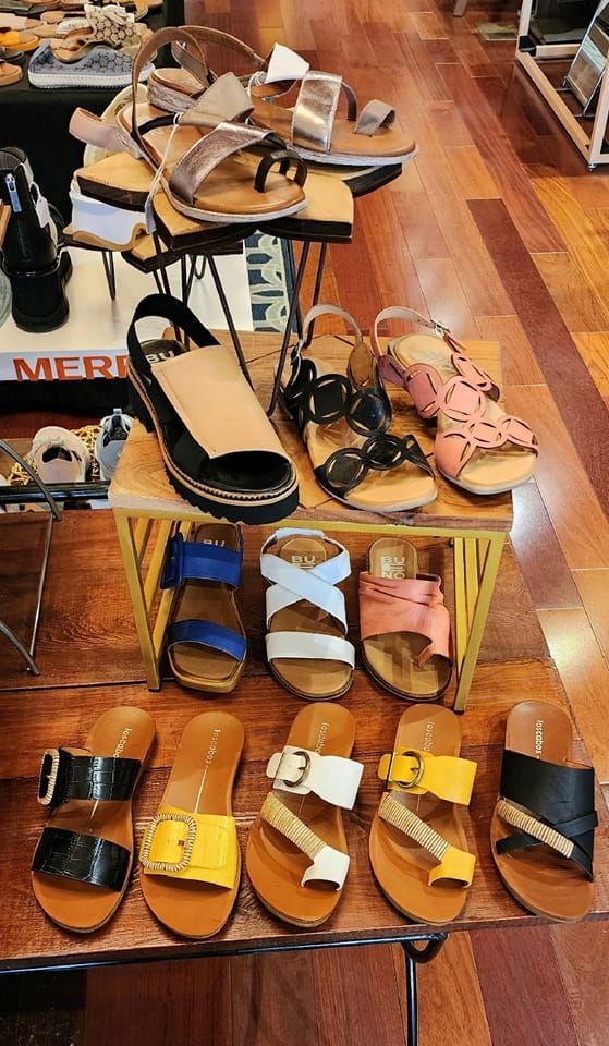 A display of sandals on a wooden table in a shoe store.