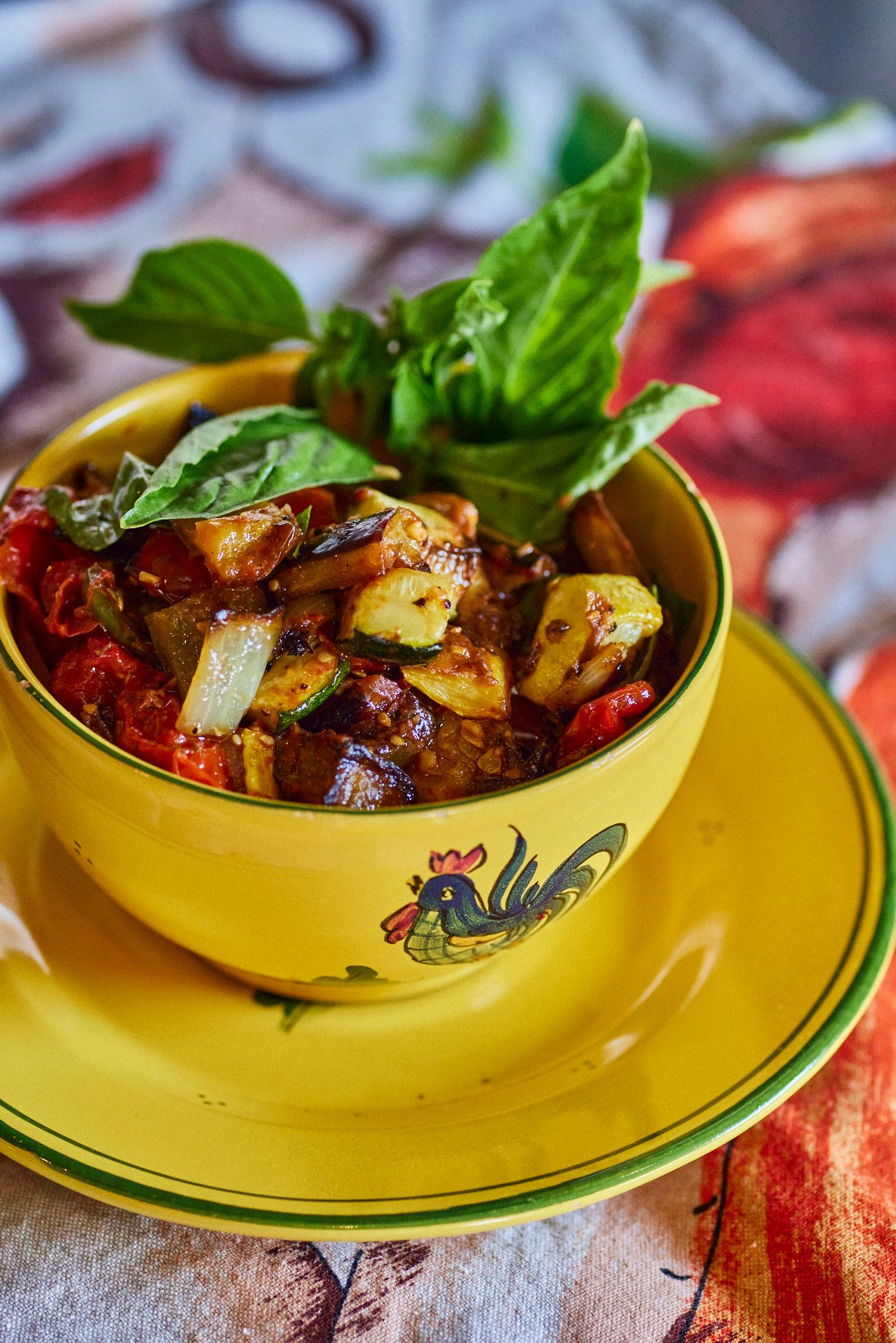 Yellow bowl of roasted vegetables with basil garnish, set on a matching plate. Mariposa Sedona