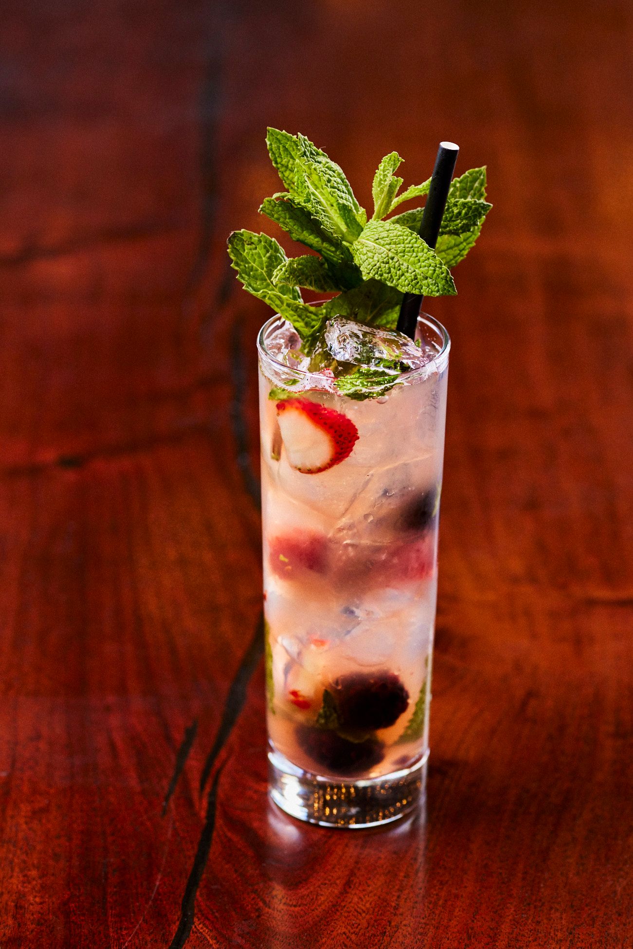 Tall cocktail with fresh mint and fruit in a glass, on a dark wooden table. Mariposa Sedona