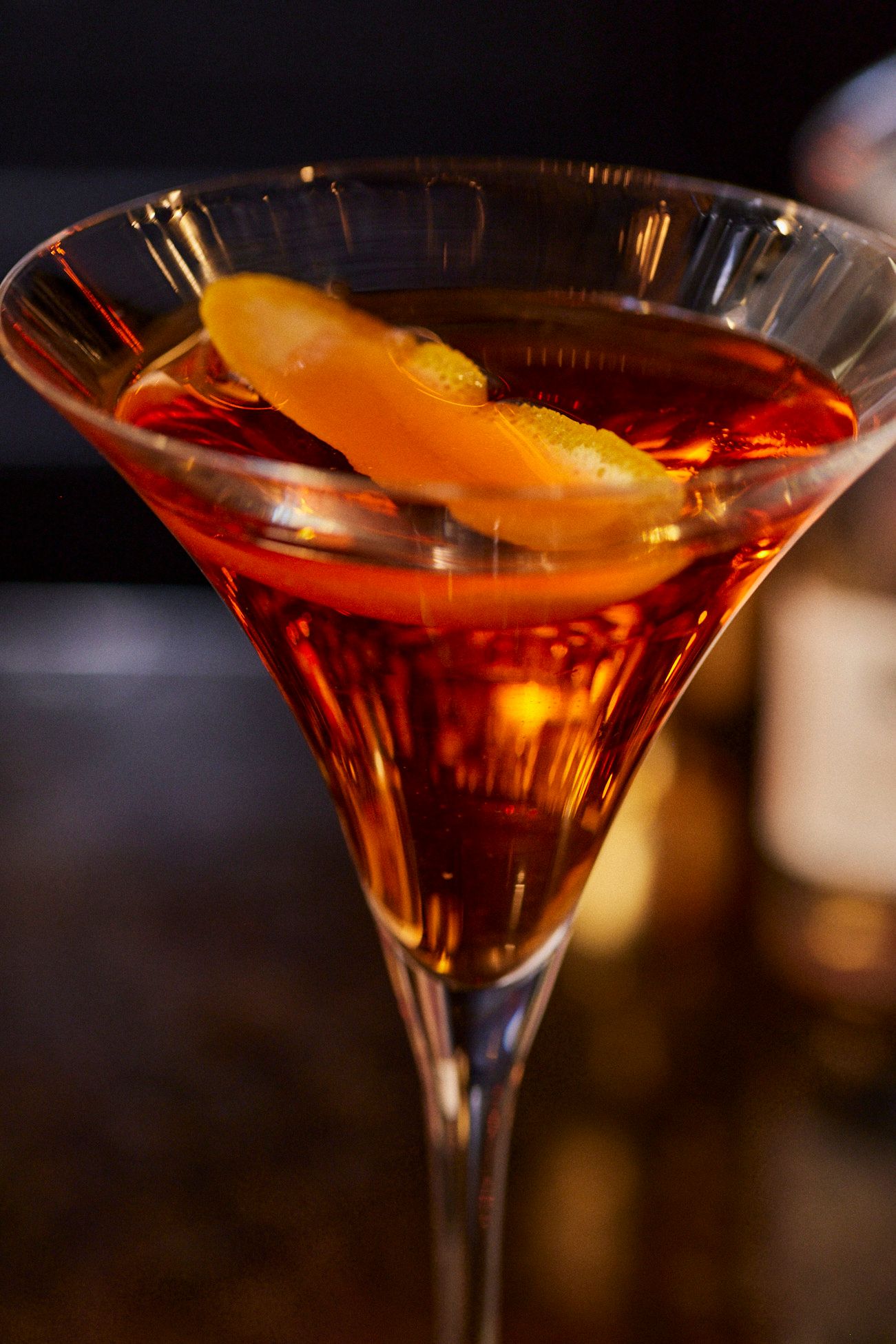 Cocktail in a martini glass, orange peel garnish, brown liquid. Mariposa Sedona