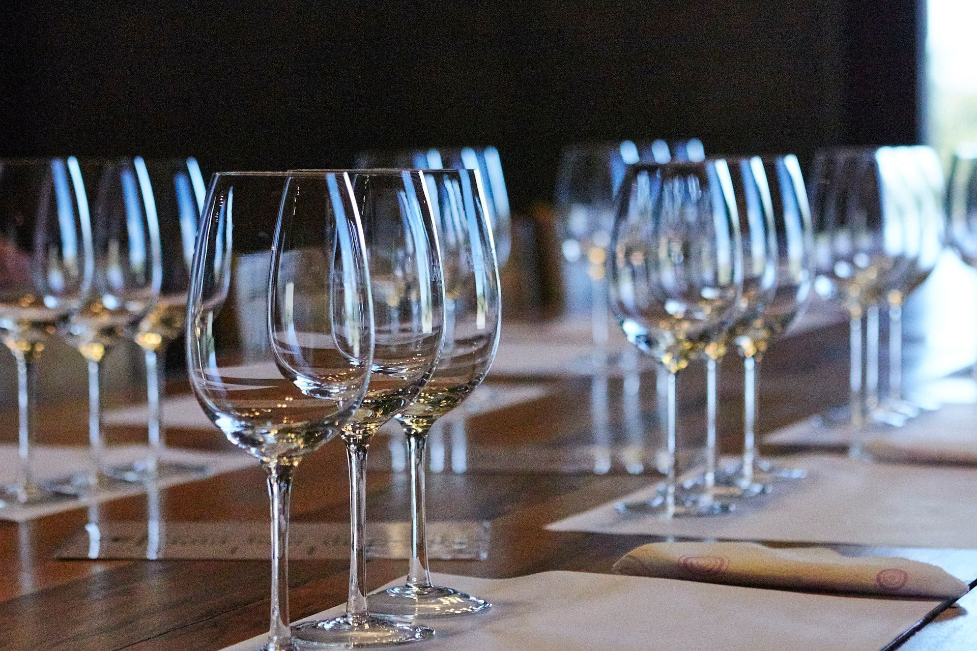 Rows of empty wine glasses on a wooden table, set for a tasting. Mariposa Sedona