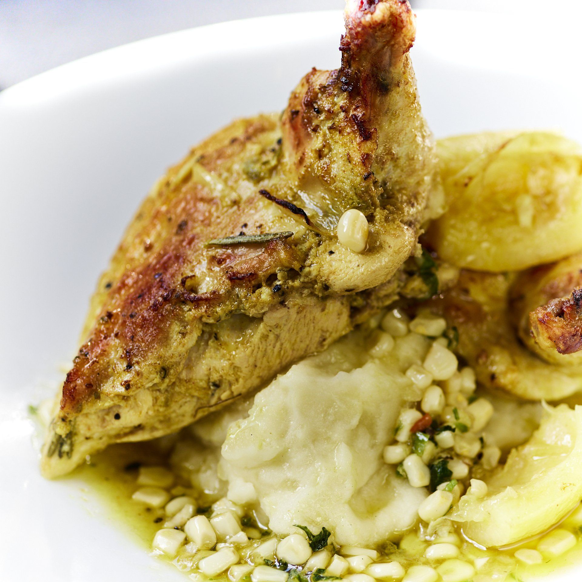 Roasted chicken breast and potatoes with mashed potatoes and corn.