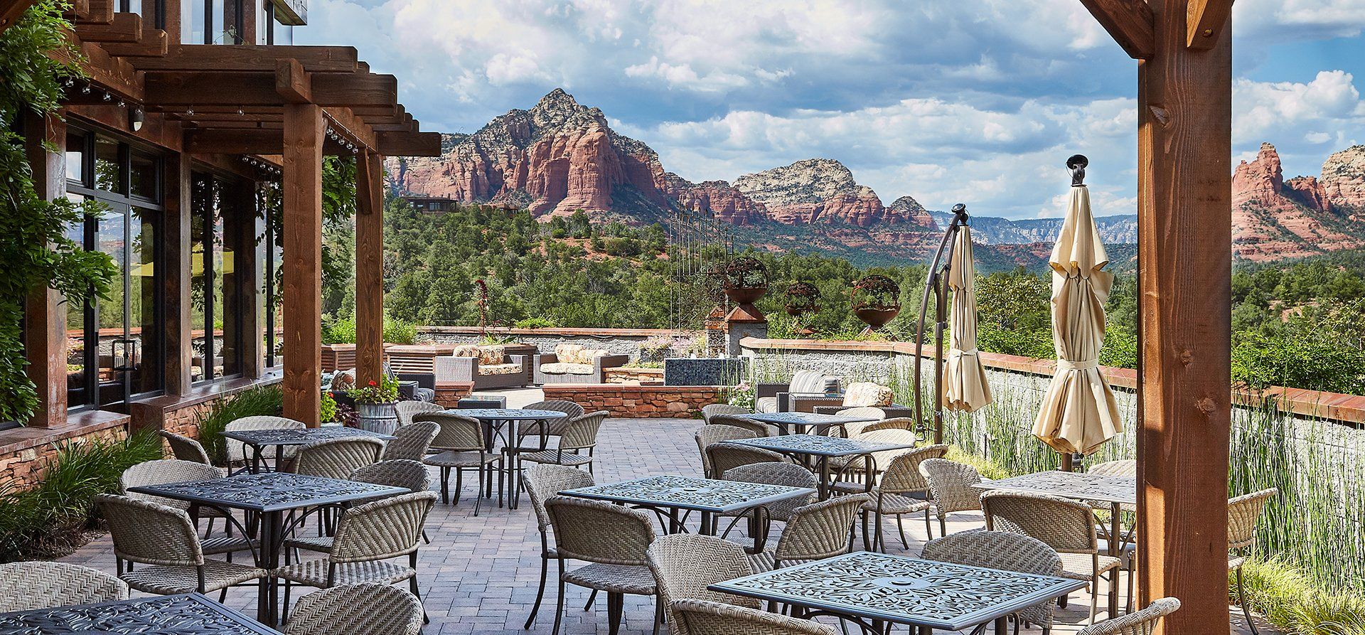Outdoor restaurant with tables and chairs overlooking red rock mountains.