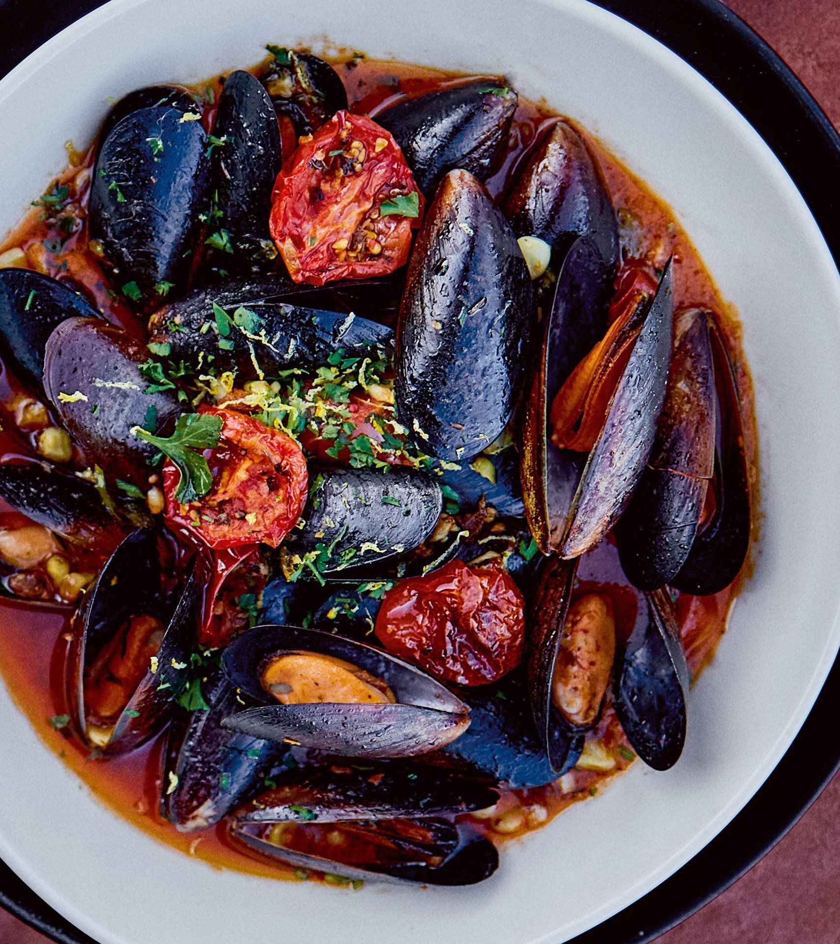 Bowl of mussels in a tomato-based broth, garnished with herbs and tomatoes. Mariposa Sedona