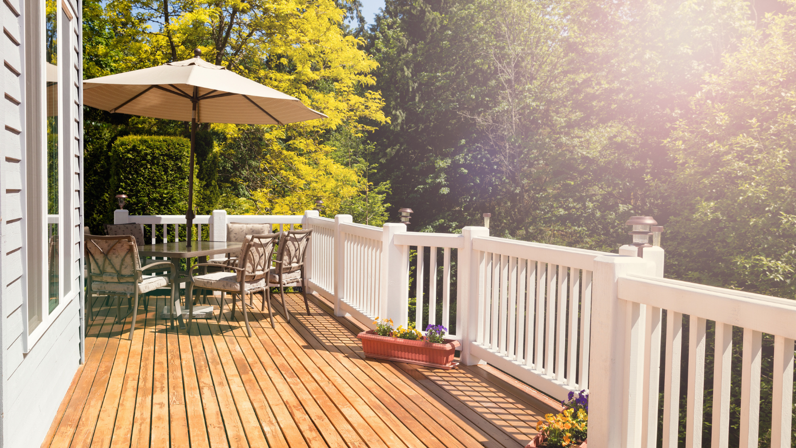A wooden deck with a white railing and umbrella.