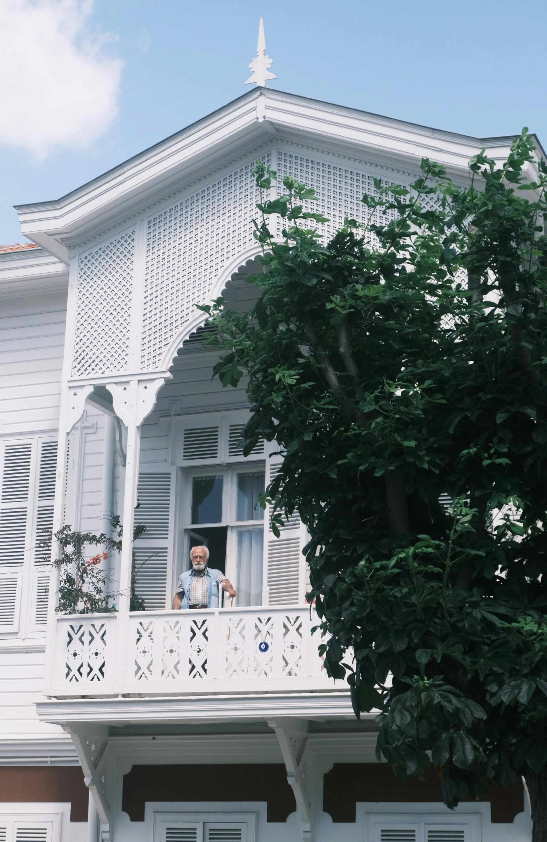 A man is standing on a balcony of a white house.