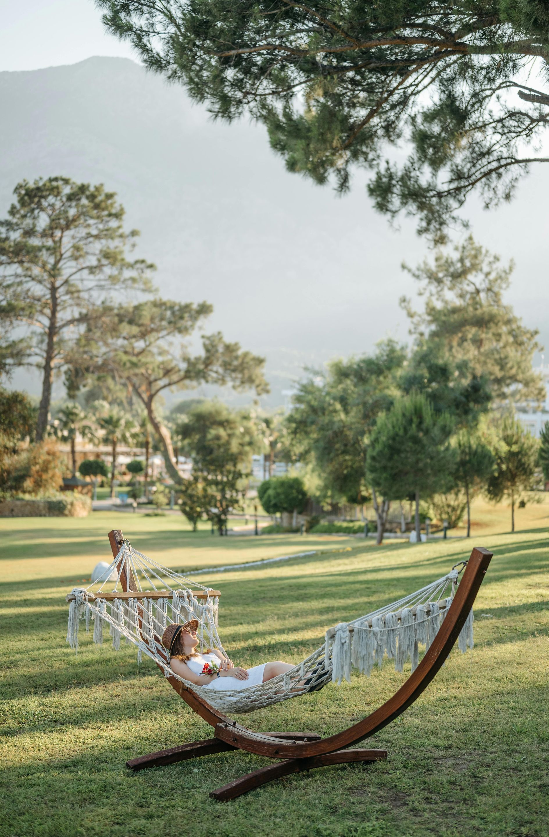A woman is laying in a hammock in a park.