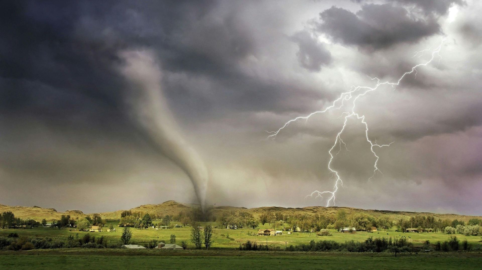 There is a tornado and lightning in the sky.