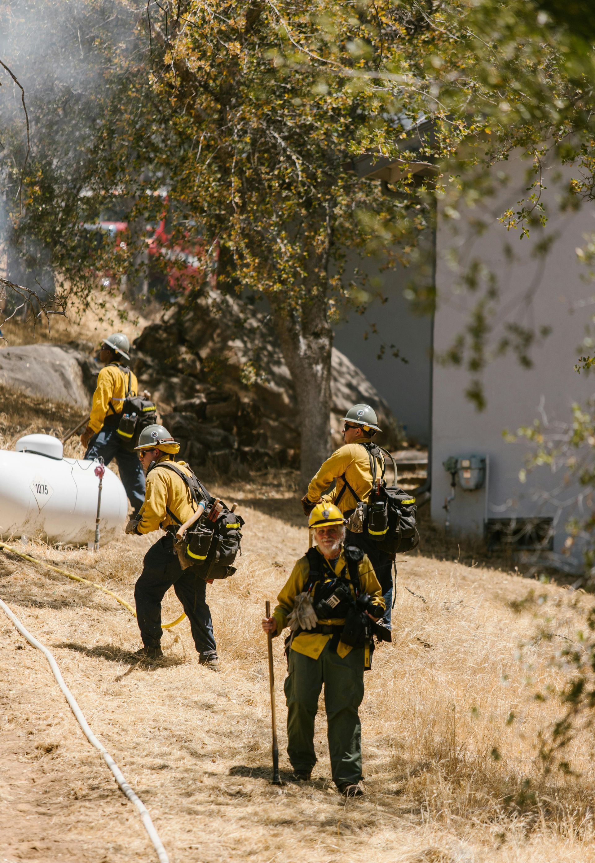 A group of firefighters are walking down a dirt road.