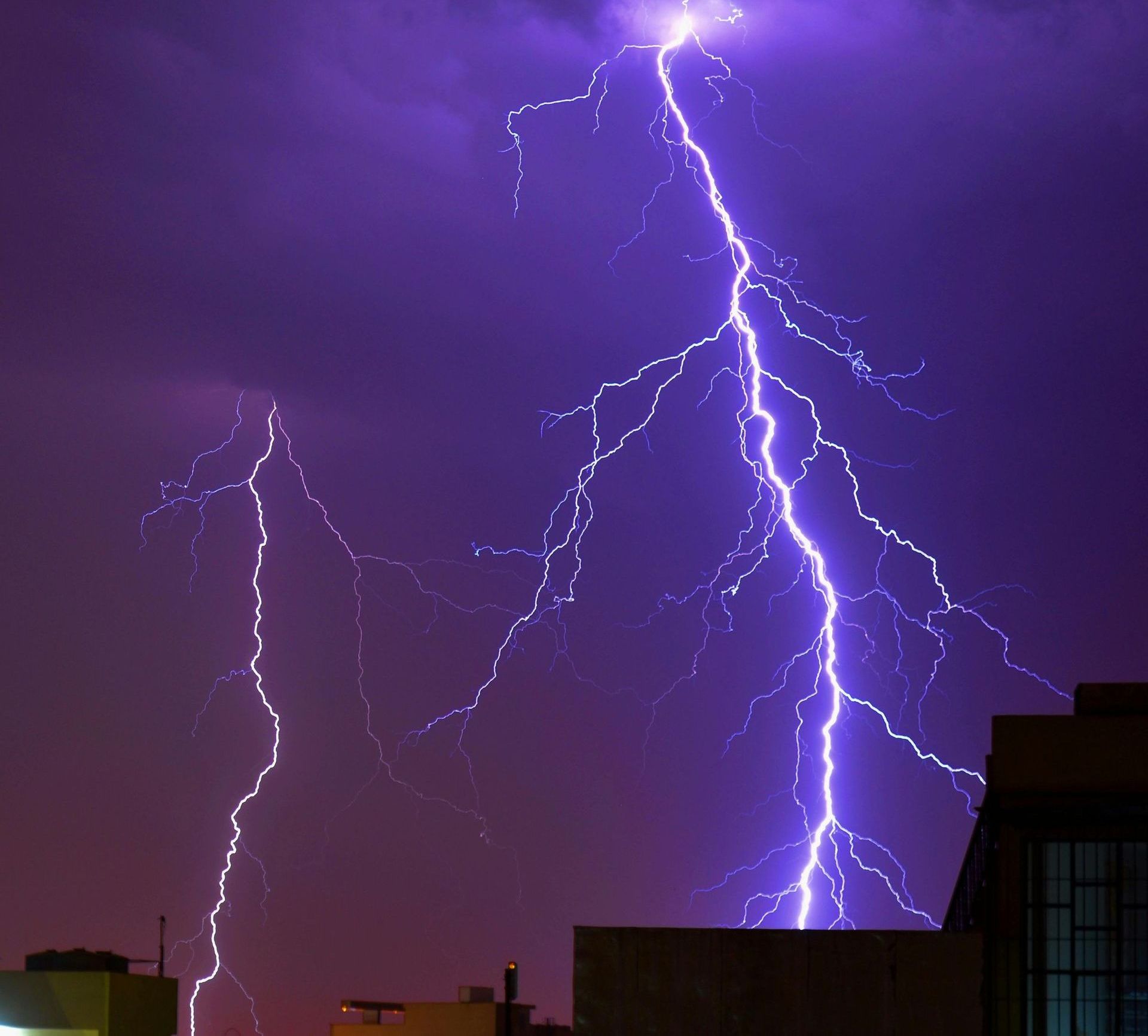 Lightning strikes in the night sky over a city