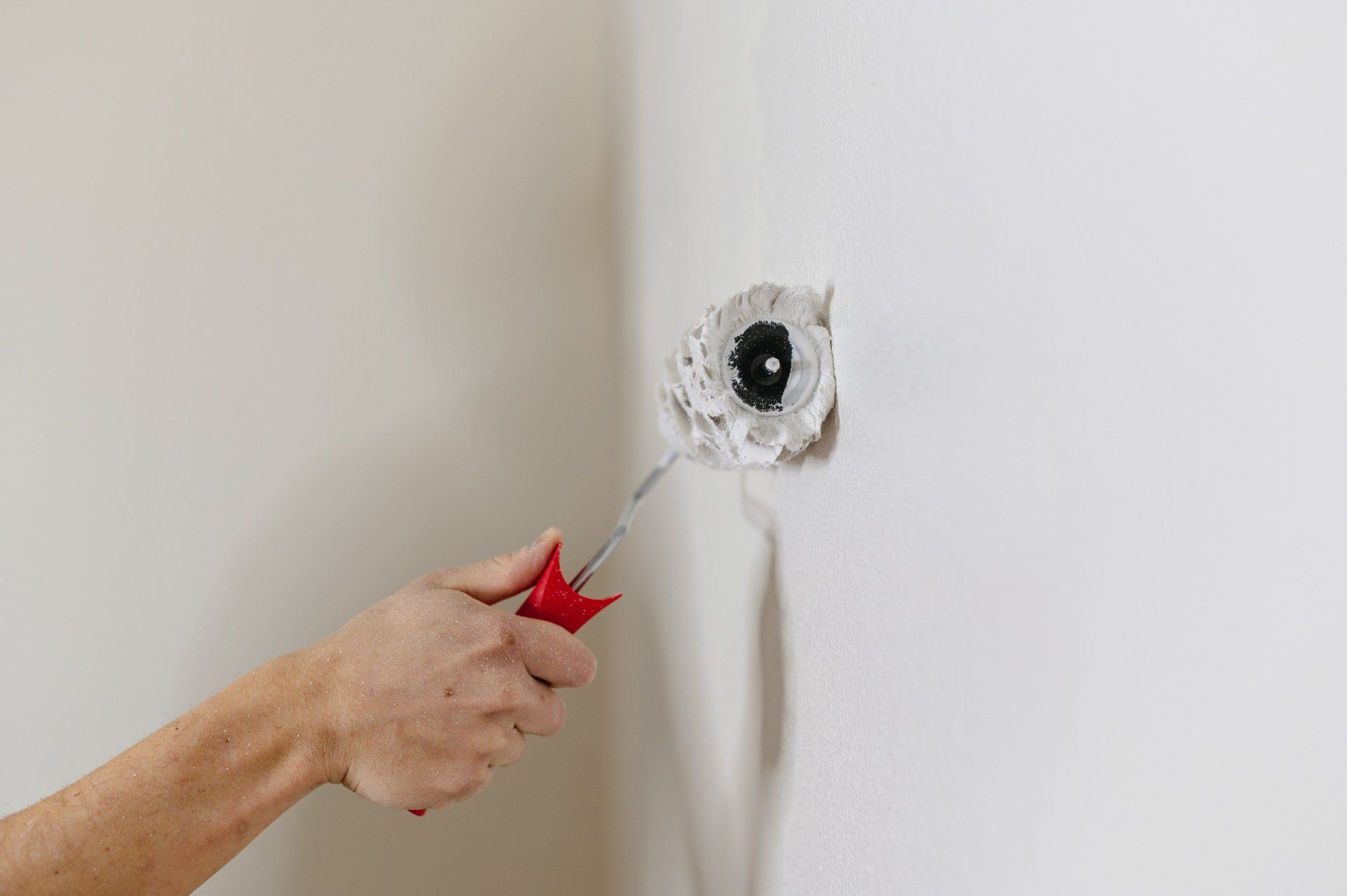 An individual applying texture to a wall using a roller, creating a unique surface pattern with smooth and even strokes.