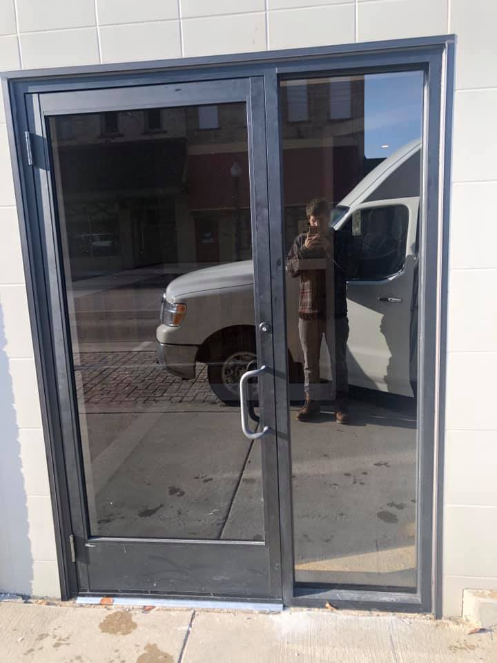 A white van is parked in front of a glass door
