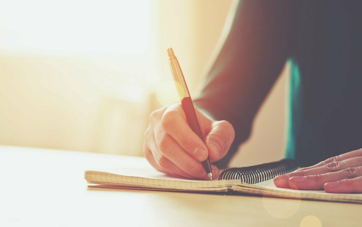Une personne écrit dans un cahier avec un crayon.