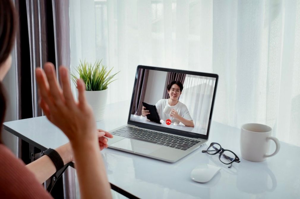 Une femme est assise à un bureau et utilise un ordinateur portable pour passer un appel vidéo.