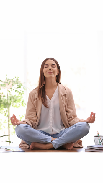 Une femme est assise sur le sol en position du lotus avec les jambes croisées.