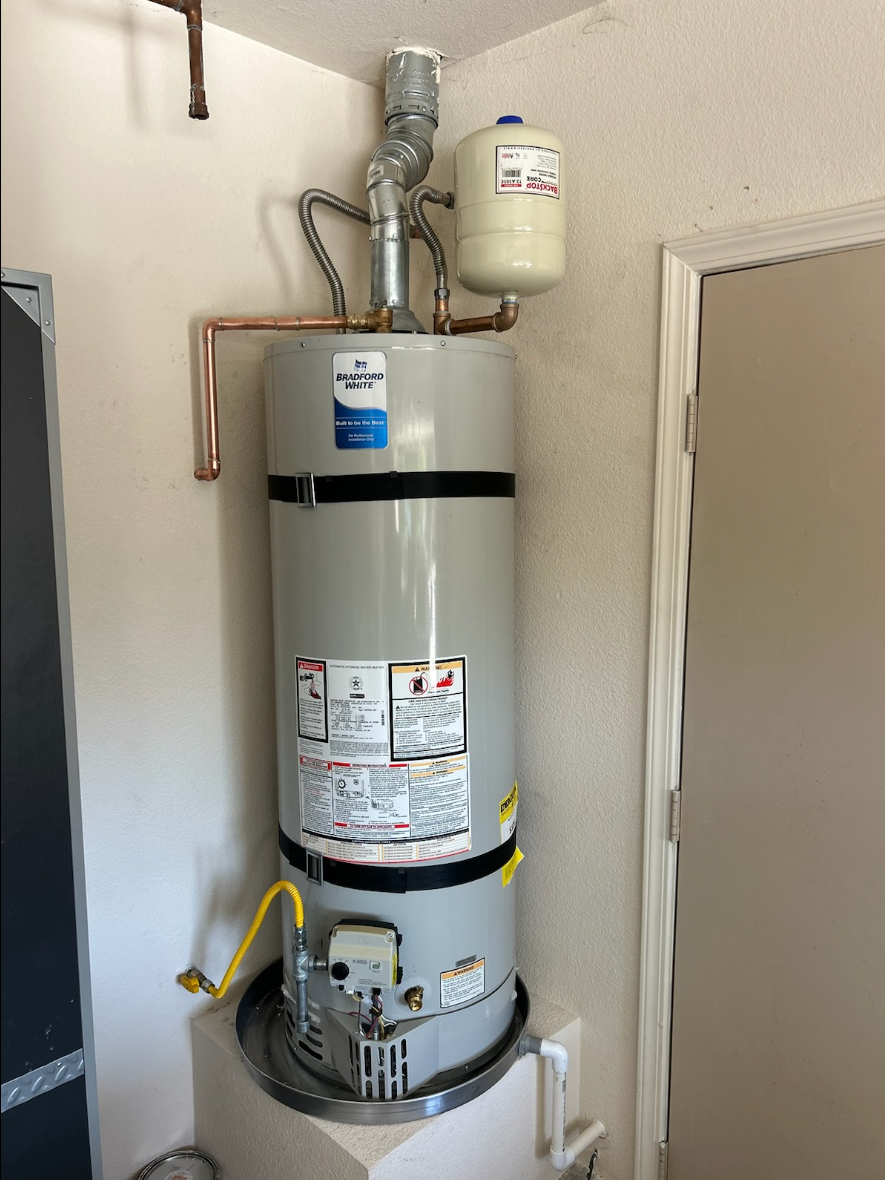 A water heater is sitting in a room next to a door.