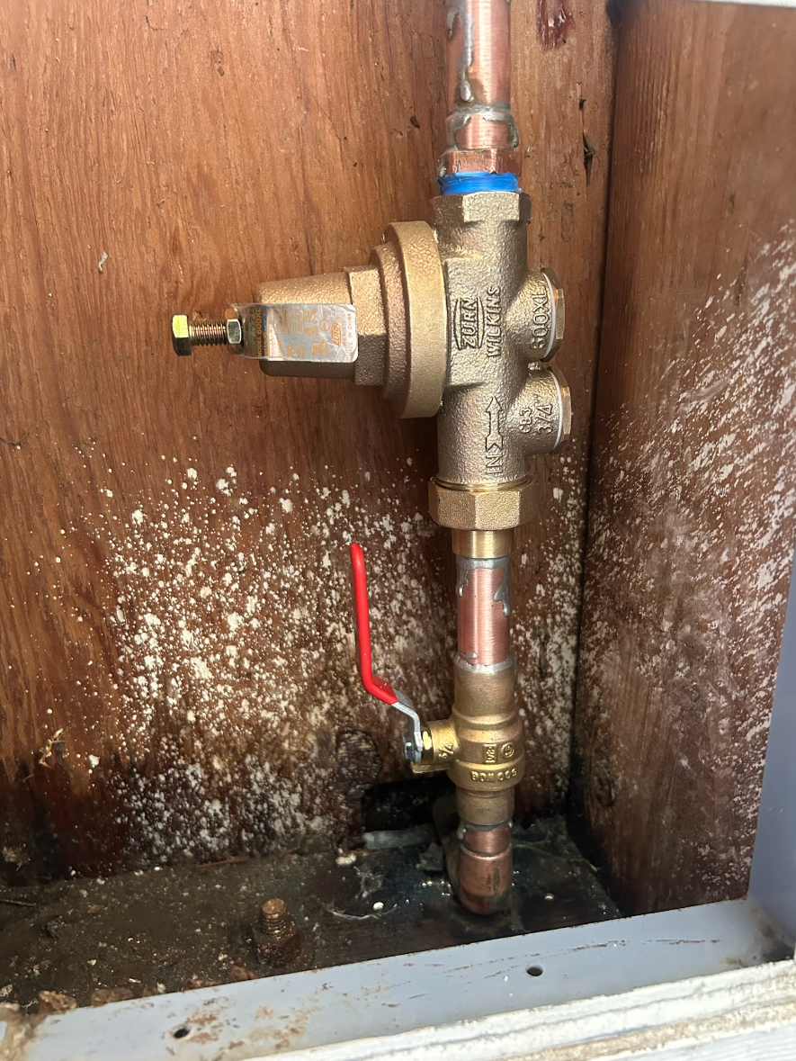 A close up of a copper pipe with a red valve attached to it.