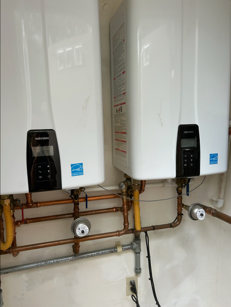 Two water heaters are hanging on a wall next to each other.