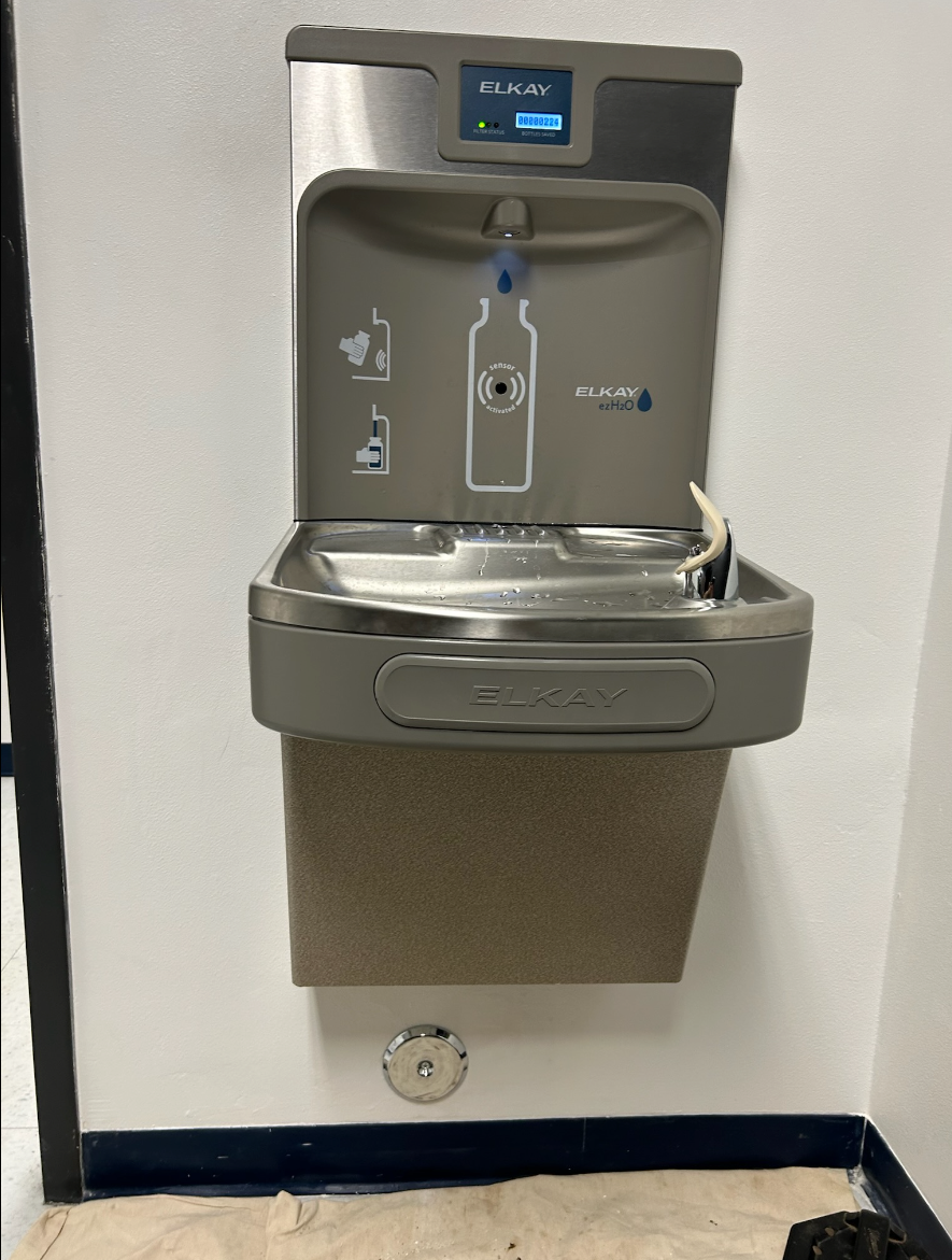 A stainless steel water fountain with a bottle on it