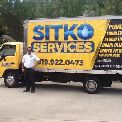 A man is standing in front of a sitko services truck