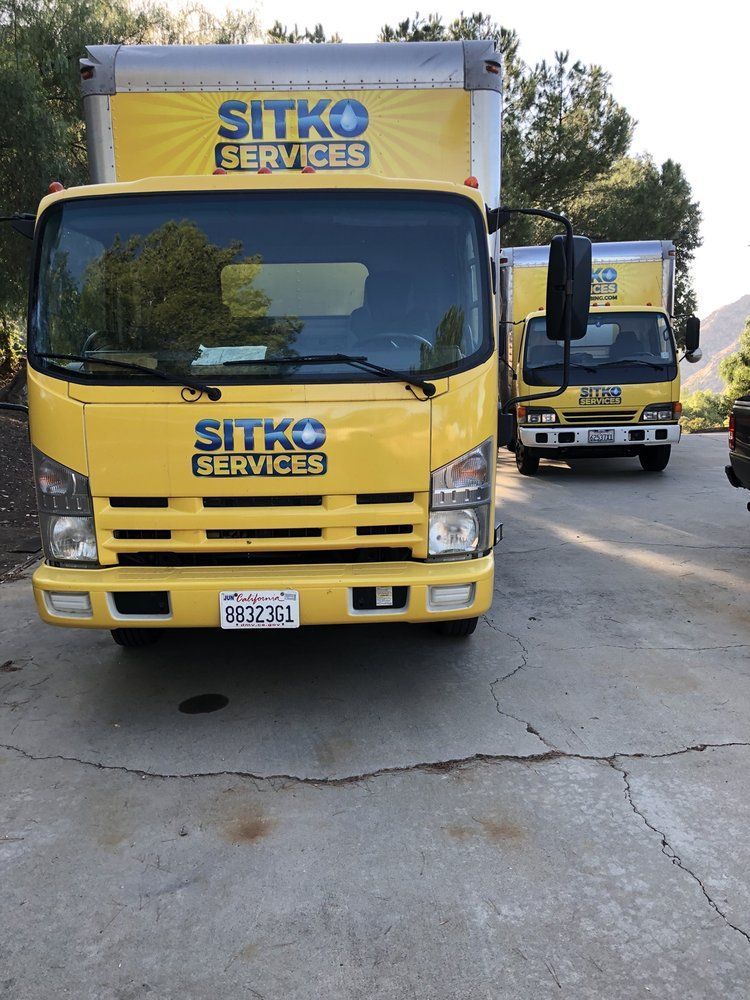 Two sitko services trucks are parked in a driveway