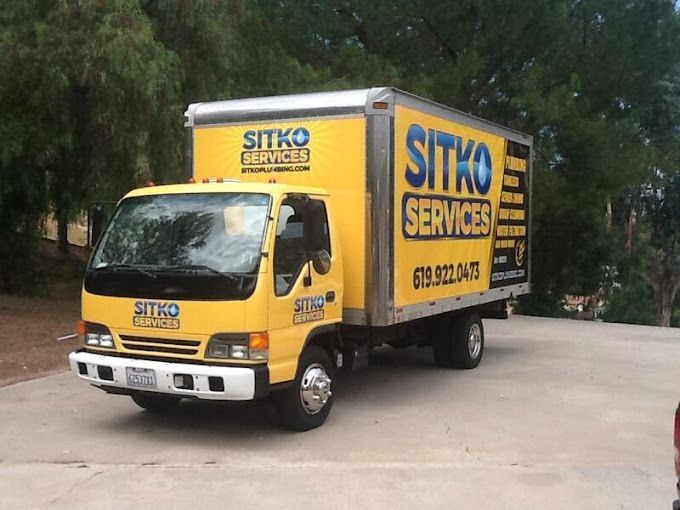 A yellow sitko services truck is parked in a driveway